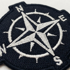 Detalhe do bordado do patch rosa dos ventos preto e branco com bússola